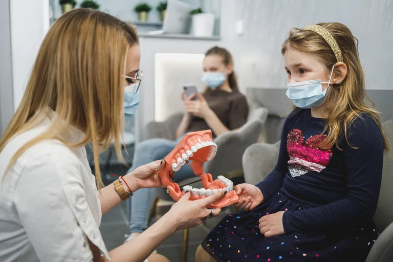 Clinician showing a young girl a model of teeth during a dental visit