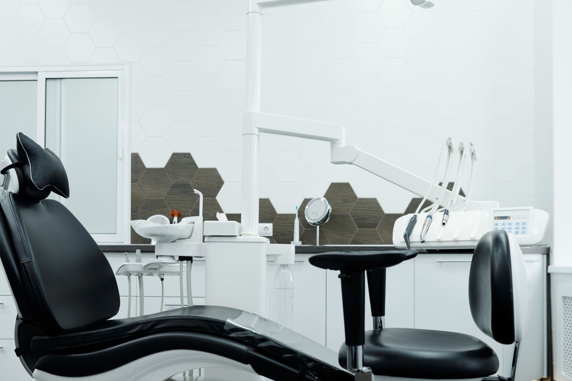 An empty dental treatment room with a black dental chair